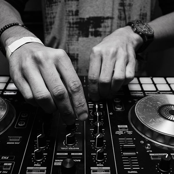Electronic music services; DJ adjusting turntable controls in black and white.