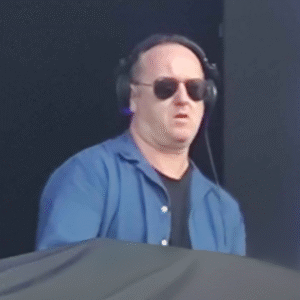 Famous EDM DJ, Sasha, headshot on stage wearing headphones and glasses.